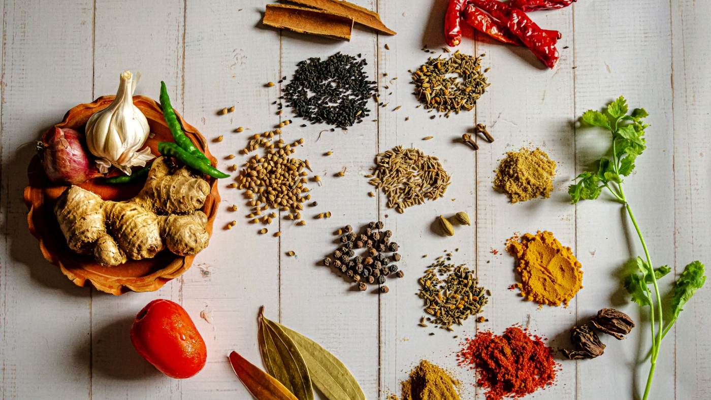 Indian spices and aromatics in saffron, red and green on a wooden table